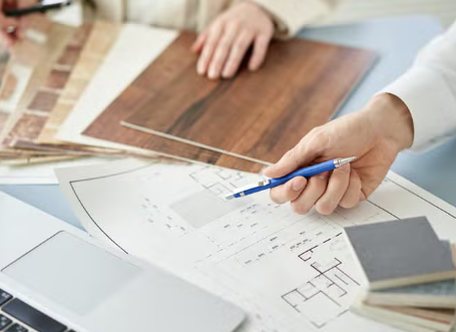 Mains disposant des échantillons de bois et de matières sur un plan d'aménagement